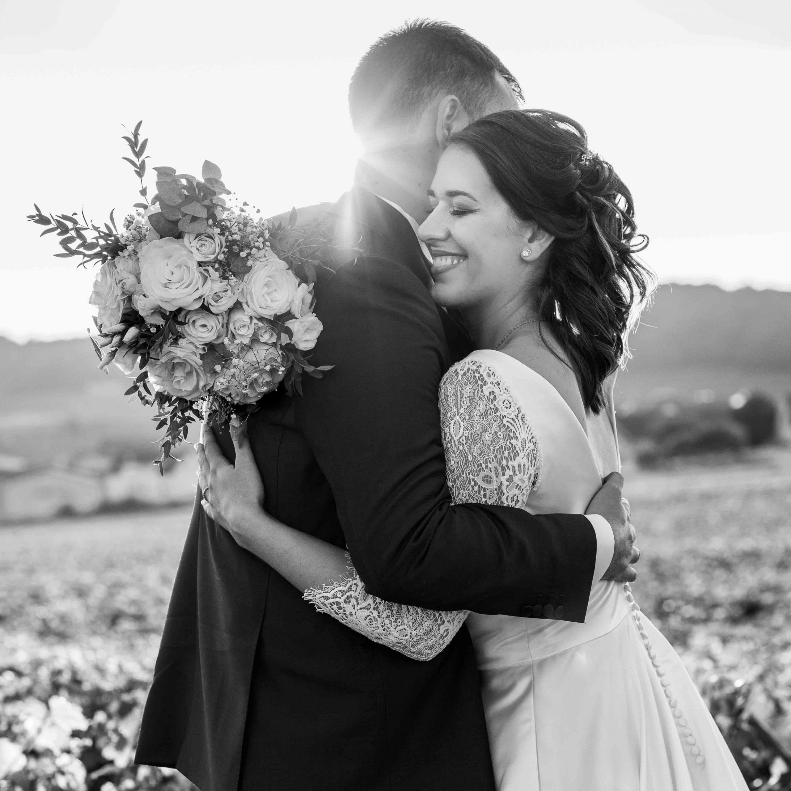 photo couple de mariés se serrant dans les bras avec joli bouquet et un sourire rayonnant