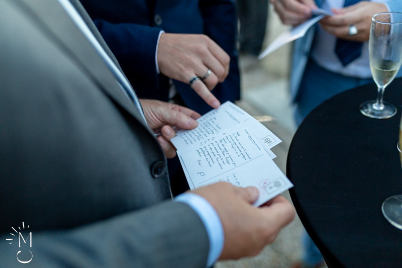 mains regardant une carte d'énigme pendant une animation lors du cocktail d'un mariage