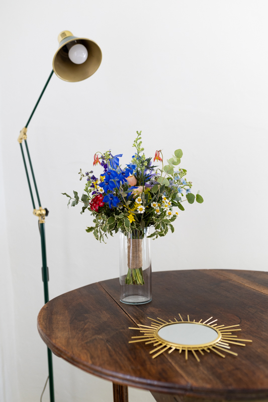 bouquet de fleur posé dans une vase sur une table avec une lampe et un miroir