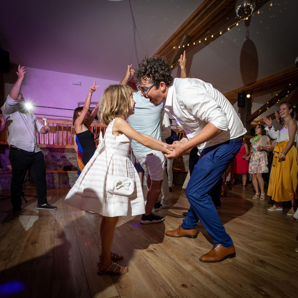 photo de soirée d'un mariage où le marié danse avec une enfant demoiselle d'honneur en la regardant dans les yeux