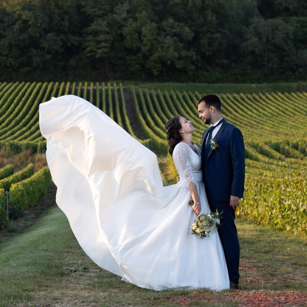 mariés au milieu des vignes avec robe qui vole