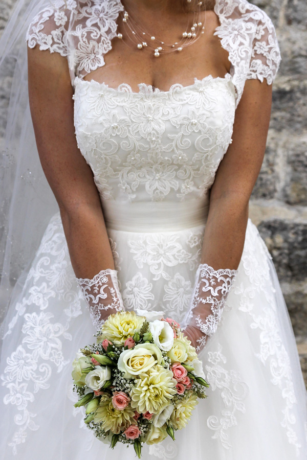 mariée tenant son bouquet devant sa belle robe de mariée