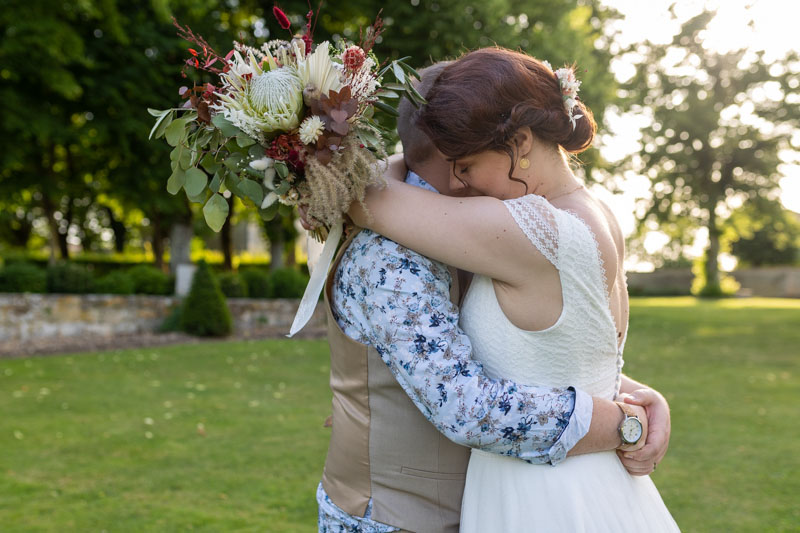 couple s'enlaçant dans les bras, la mariée a un joli bouquet