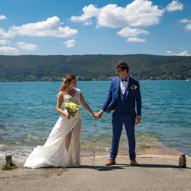 deux mariés se tiennent la main et se regardent, le lac du bourget derrière eux